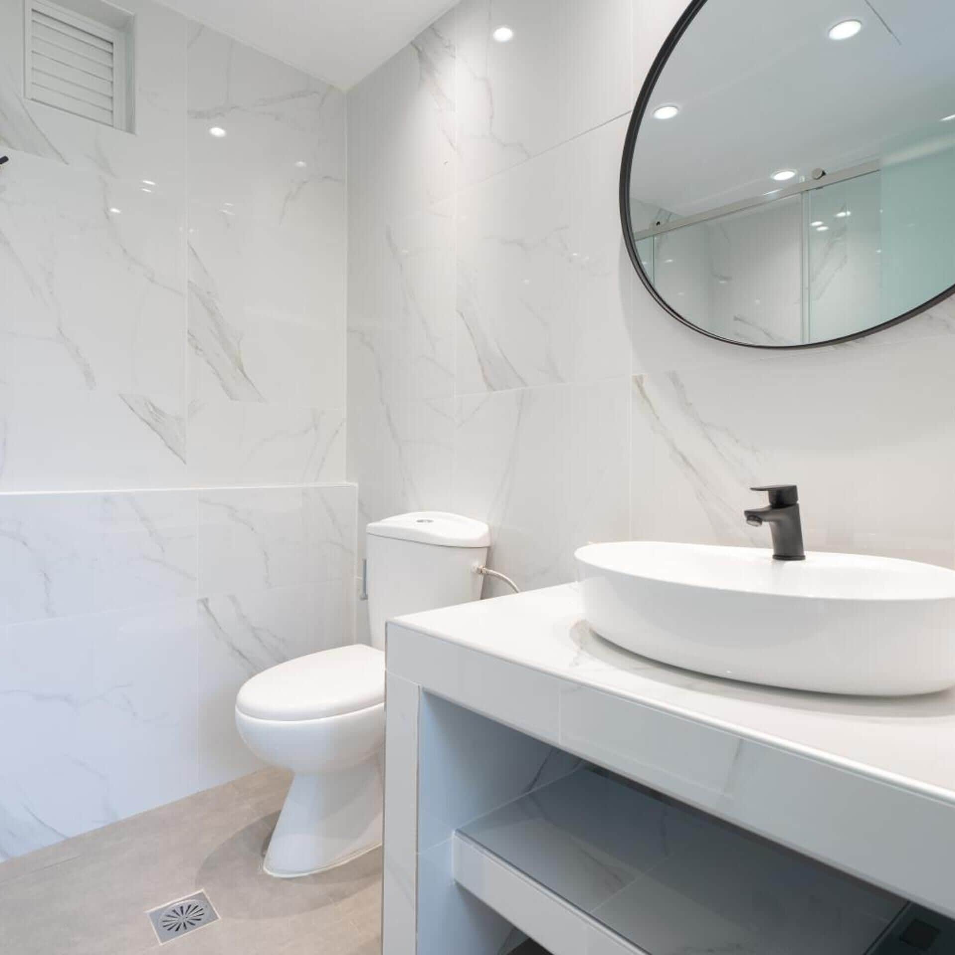 Un baño moderno con inodoro, lavamanos y espejo.