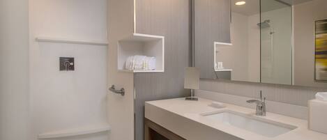 A modern bathroom with a bathtub, two sinks, a large mirror, and a towel rack.