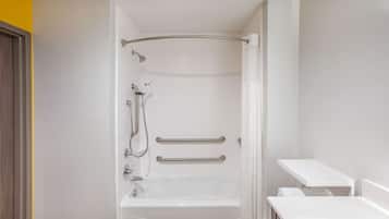 Een moderne badkamer met een witte badkuip, handgrepen en een douchegedeelte.