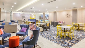 Un moderno vestíbulo de hotel con áreas de estar, mesas y una alfombra estampada.