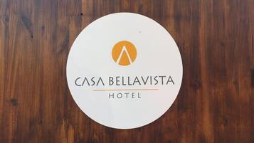 Un letrero circular con el texto 'CASA BELLA VISTA HOTEL' y un logotipo estilizado de 'M'.