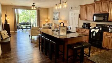A spacious kitchen with wooden cabinets, a central island with bar stools, and a dining area with a view to the outdoors.