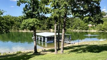 A lakeside view with a gazebo, trees, and a building in the background.