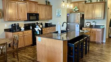 A kitchen with wooden cabinets, a central island, a refrigerator, and a coffee maker.