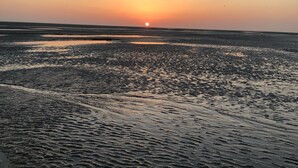 A beach at sunset with wet sand reflecting the sky.