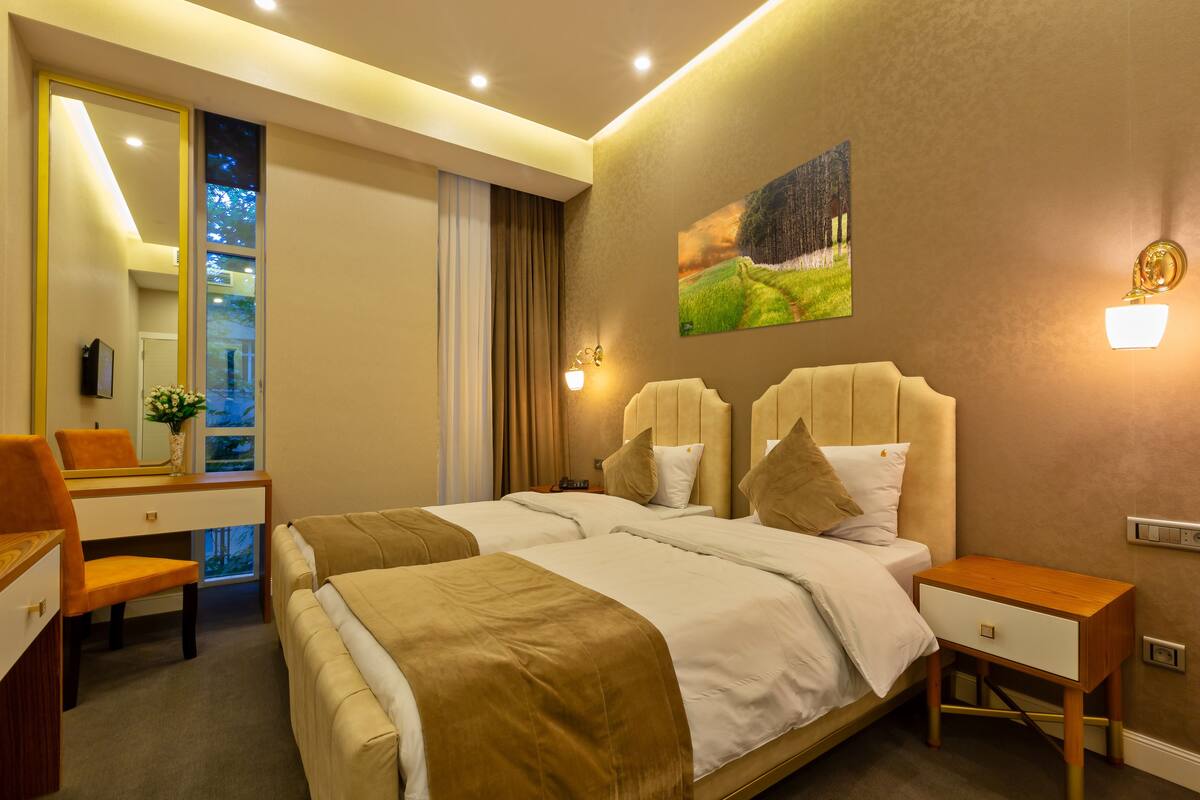 A hotel room with two beds, a desk, and a chair.