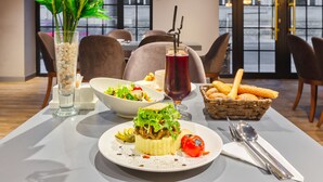 A dining table with a salad, a red drink, bread, and a basket of breadsticks. - Aksent Hotel (Baku)