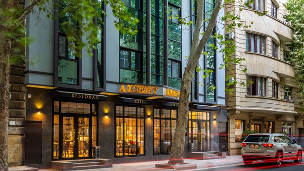 A hotel with a restaurant on the ground floor, large windows, and a tree in front. - Aksent Hotel (Baku)