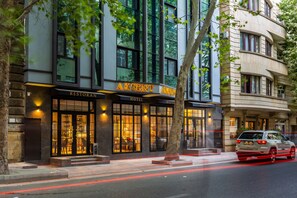 A hotel with a restaurant on the ground floor, large windows, and a tree in front. - Aksent Hotel (Baku)