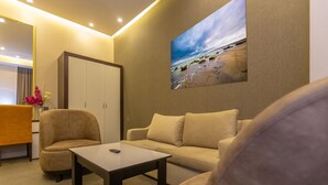 A modern room with a sofa, armchairs, a coffee table, and a painting of a beach scene. - Aksent Hotel (Baku)