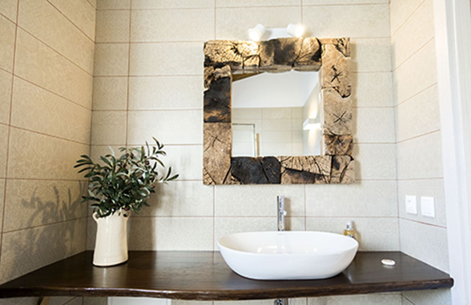 Une salle de bain avec un lavabo blanc, un miroir décoratif et une plante en pot.