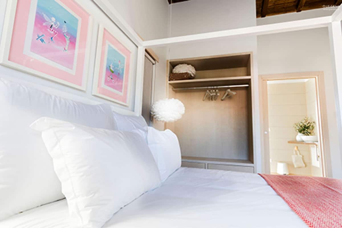 A bedroom with a bed, a wardrobe, and a door leading to another room.