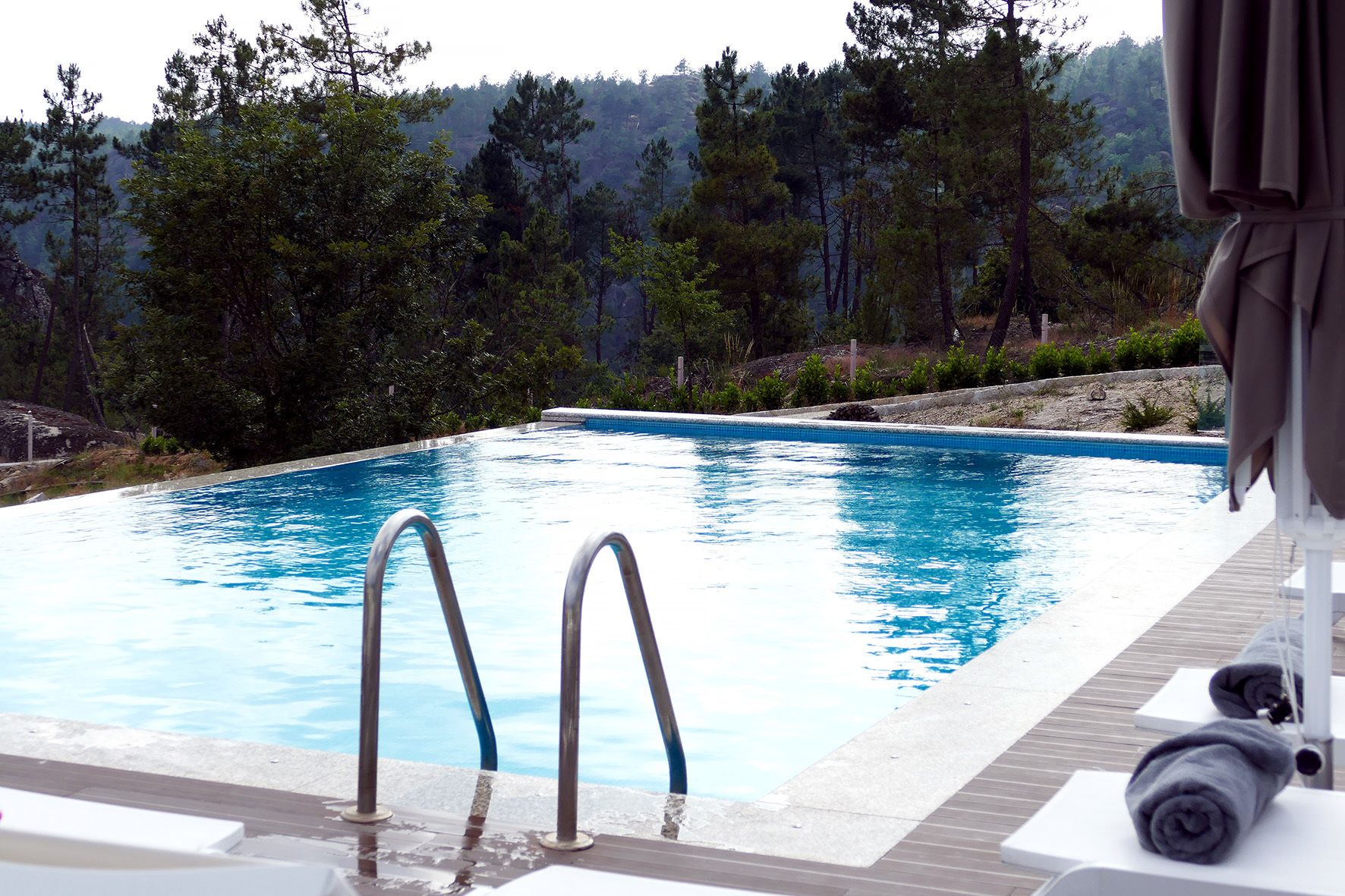 Una piscina al aire libre, sombrillas, sillones reclinables de piscina
