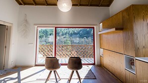 A room with a wooden ceiling, a large sliding glass door leading to a balcony, and a wooden cabinet. - Moinho da Lapa (Sernancelhe)