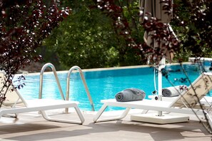 Una piscina al aire libre, sombrillas, tumbonas