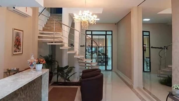 A modern interior with a staircase, a chandelier, and a seating area. - Hotel Loureiro (Rio Branco)