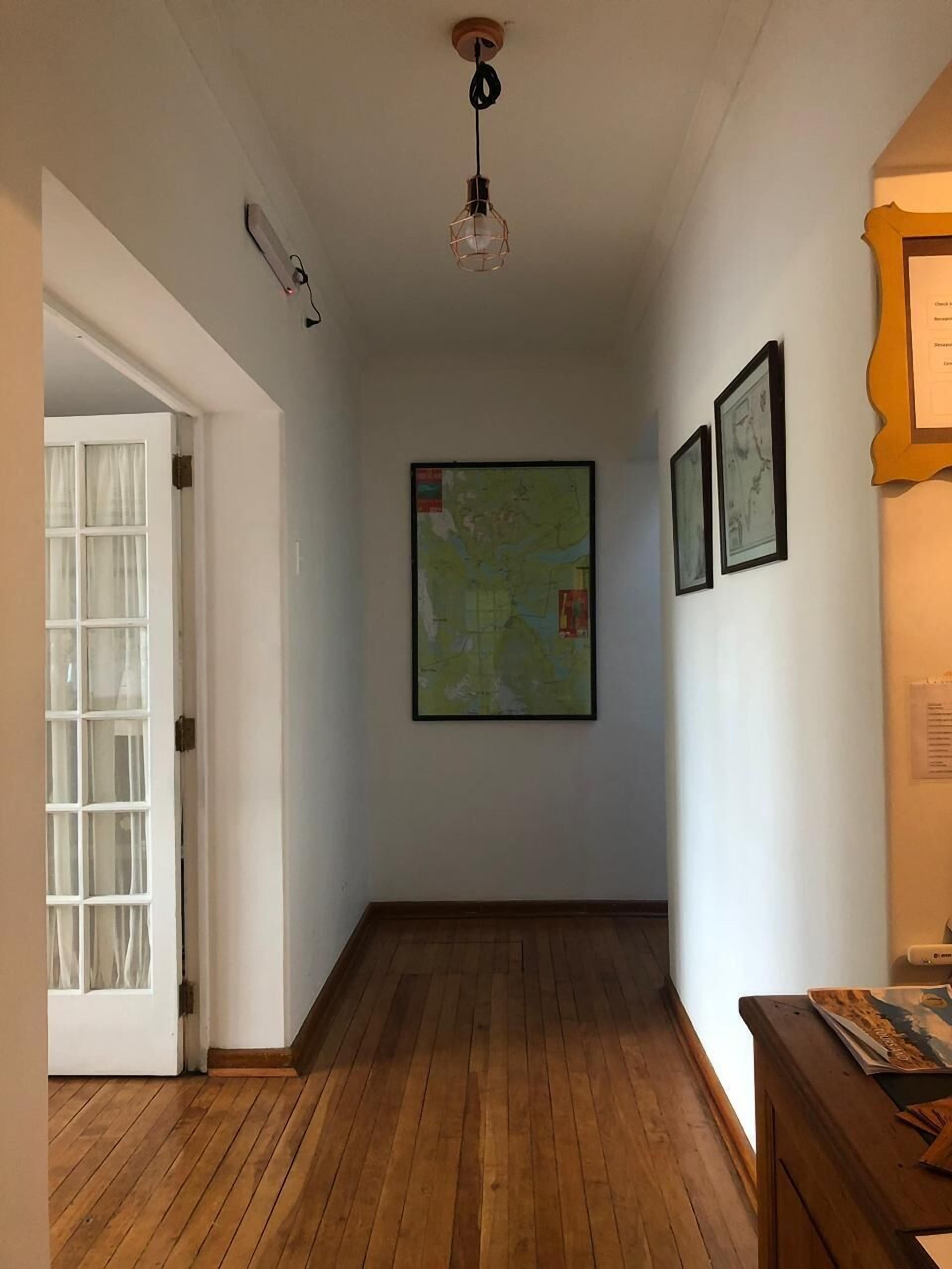 Un couloir avec un plancher en bois, une carte accrochée au mur et une porte sur le côté gauche.