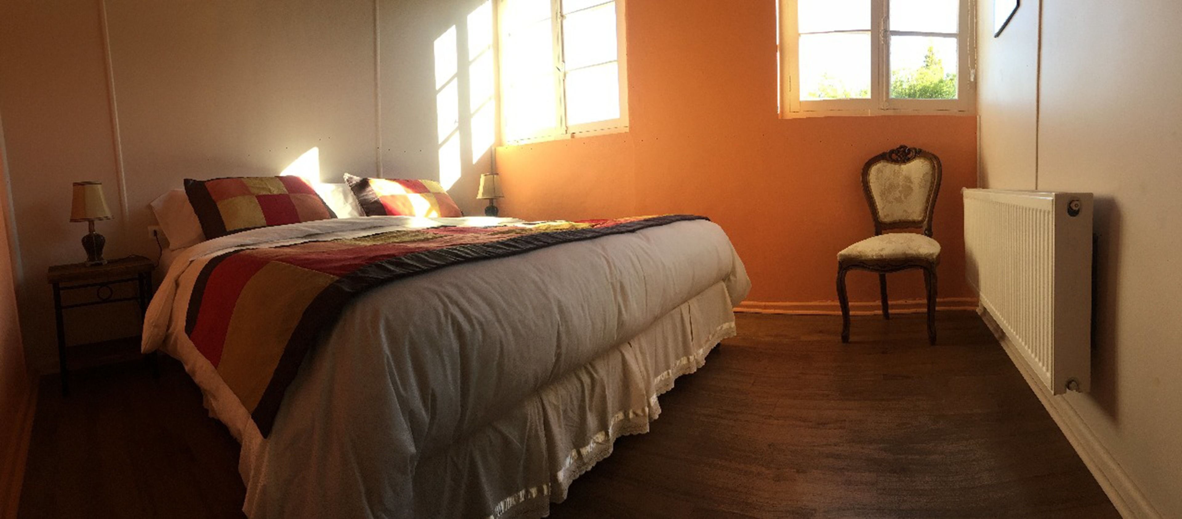 Una camera da letto con un letto grande, una sedia, un comodino e una finestra.
