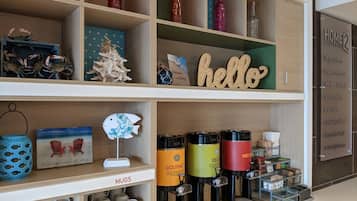A hotel reception area with a 'hello' sign, mugs, coffee makers, and various decorative items on shelves.