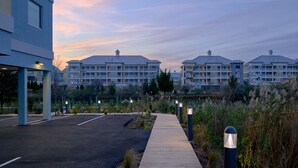Un hotel frente al agua con un paseo marítimo de madera, un estacionamiento y vistas al lago.