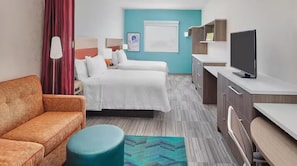 Una habitación de hotel con cama, sofá, televisión, escritorio y ventana.