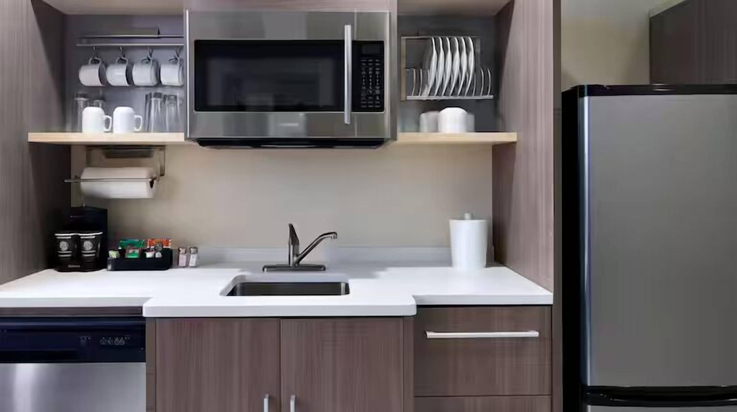 A modern kitchen with a stainless steel refrigerator, a built-in microwave, a coffee machine, and a dishwasher.