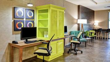 Un espacio de oficina moderno con un escritorio de madera, dos sillas de oficina, un archivador verde y un monitor de computadora.