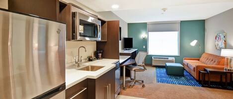 Un espacio habitable compacto con kitchenette, zona de comedor y sala de estar con sofá y mesa de centro.