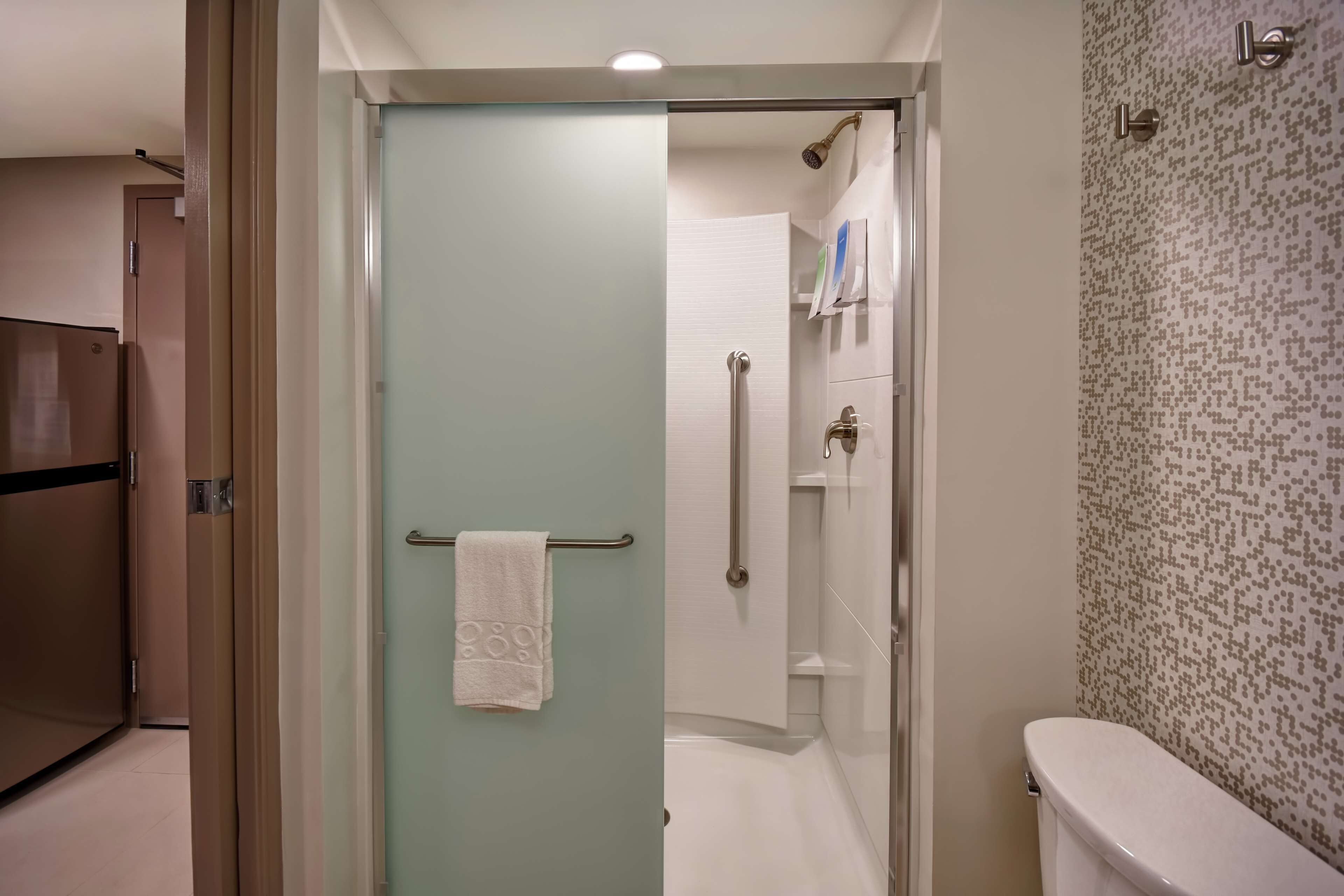 Un baño con mampara de vidrio, inodoro blanco y pared con diseño.
