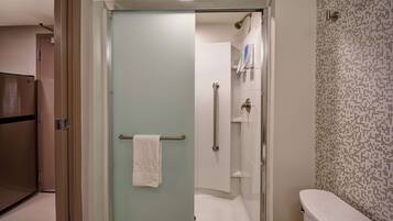 Un baño con mampara de vidrio, inodoro blanco y pared con diseño.