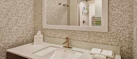 A bathroom with a white sink, a mirror, and a patterned wall.