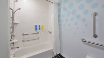 A modern bathroom with a white bathtub, grab bars, and a shower with a curtain.