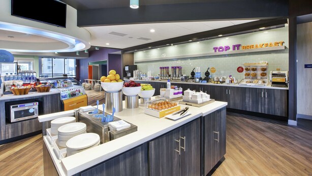Un espace moderne dédié au petit-déjeuner, avec un buffet proposant divers plats et une pancarte indiquant : « PETIT-DÉJEUNER À VOLONTÉ ».