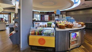 Un espace réservé au petit-déjeuner, avec un comptoir où sont exposées des boissons et des en-cas, ainsi qu’un réfrigérateur contenant des glaces.
