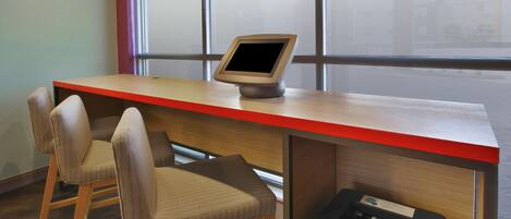 Un escritorio moderno con un monitor de computadora, dos sillas e impresora.