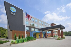 A modern hotel with a prominent 'tru' logo, a flag, and a covered entrance.