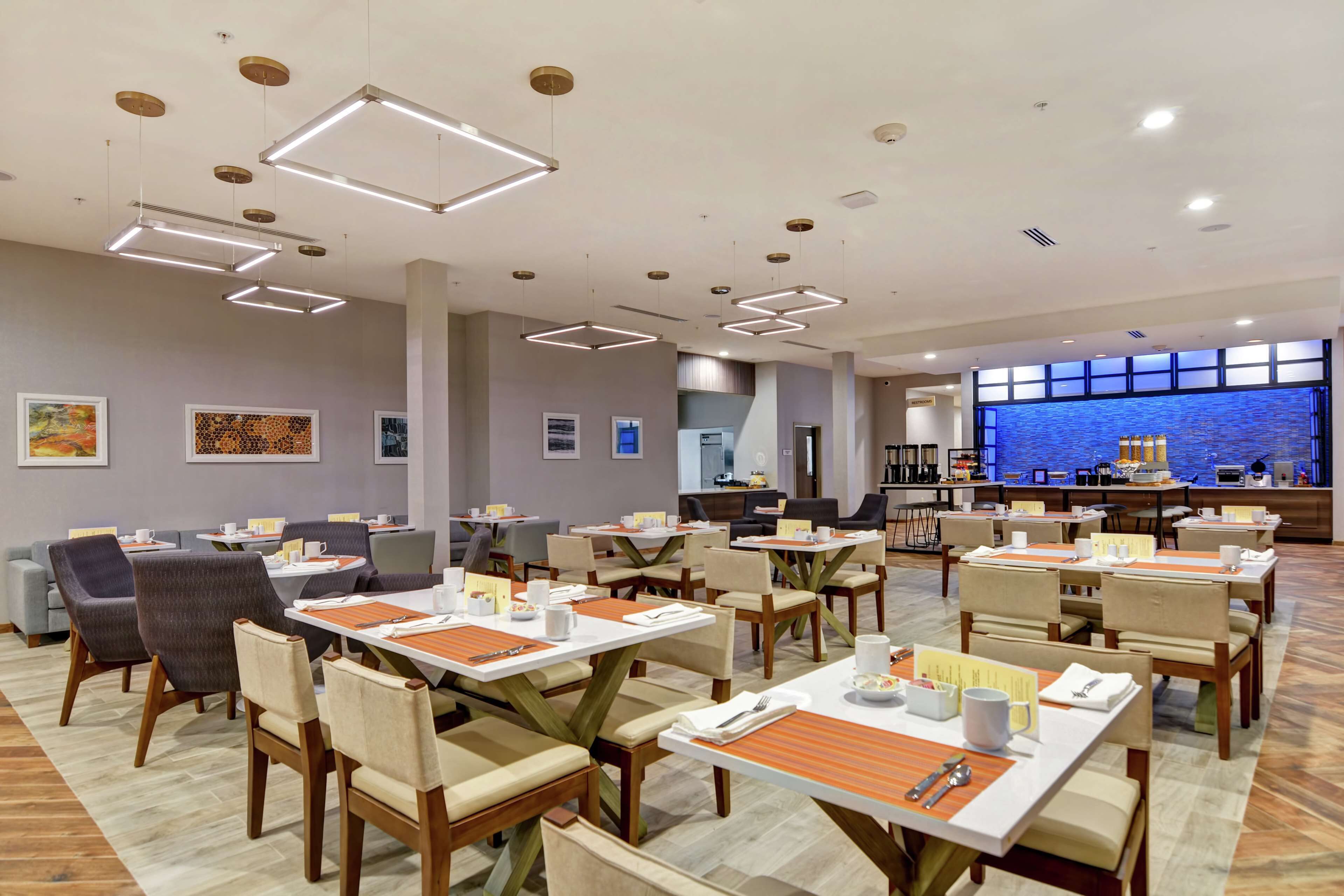 A modern dining area with rectangular tables, chairs, and overhead lighting.