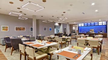 A modern dining area with rectangular tables, chairs, and overhead lighting.