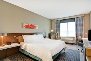 A hotel room with a bed, a desk, a chair, a TV, and a window with curtains. - Hilton Garden Inn Princeton Lawrenceville (Lawrenceville)