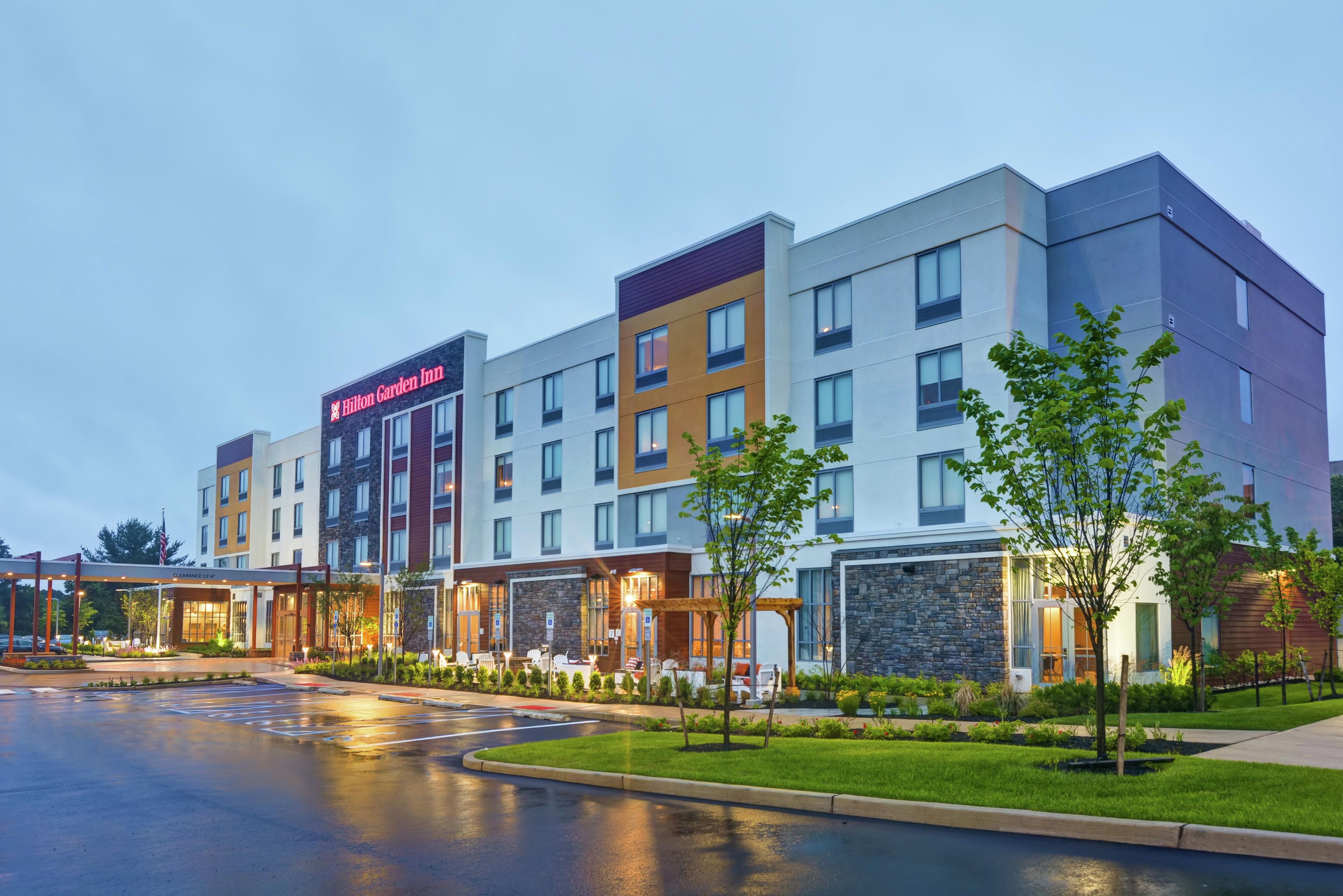 A multi-story hotel with a clear entrance, outdoor seating, and a parking lot.
