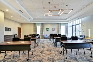 A conference room with tables and chairs, a patterned carpet, and large windows. - Hilton Garden Inn Princeton Lawrenceville (Lawrenceville)