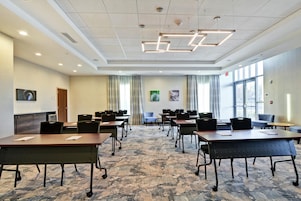 A conference room with tables and chairs, a patterned carpet, and large windows.