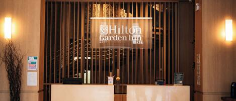 Un mostrador de recepción con un letrero que dice "Hilton Garden Inn" y una decoración interior de madera.