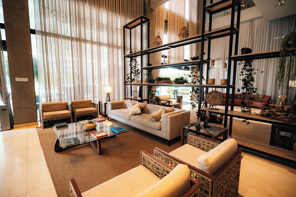 A spacious living area with a large sofa, a coffee table, and a bookshelf filled with decorative items. - Hilton Garden Inn Itajai Praia Brava (Itajai)