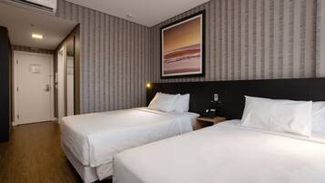 Quarto de hotel com duas camas, um quadro grande na parede e piso de madeira.