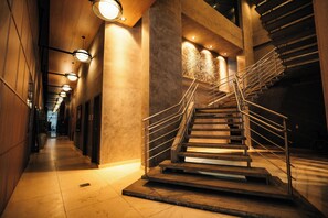 A modern interior with a central staircase, polished stone walls, and recessed lighting. - Hilton Garden Inn Itajai Praia Brava (Itajai)