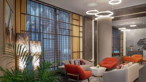 A modern hotel lobby with a sofa, armchairs, a coffee table, and a large window with curtains. - Hilton Beirut Downtown (Beirut)
