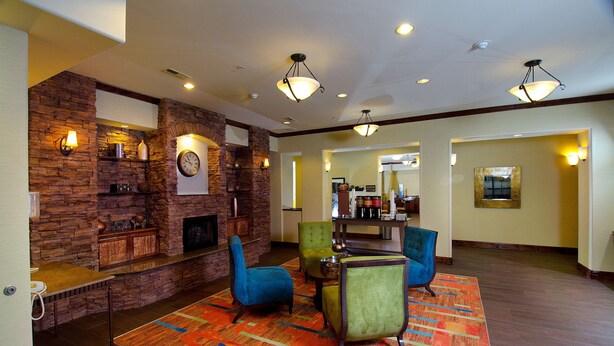 A lobby with a stone wall, a fireplace, and a seating area with chairs. - Hampton Inn & Suites Gallup (Gallup)