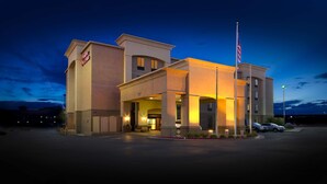 A hotel with a modern design, featuring a prominent entrance and an American flag. - Hampton Inn & Suites Gallup (Gallup)