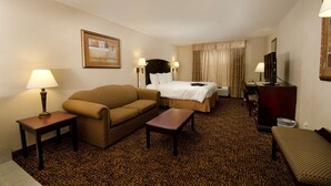 A hotel room with a bed, a sofa, a small table, a TV, and a lamp. - Hampton Inn & Suites Gallup (Gallup)
